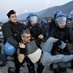 Poliziotti che trascinano un anziano manifestante.